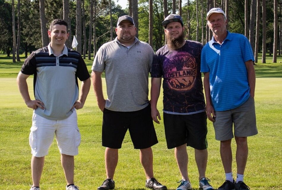group photo of four male golfers at golf tournament